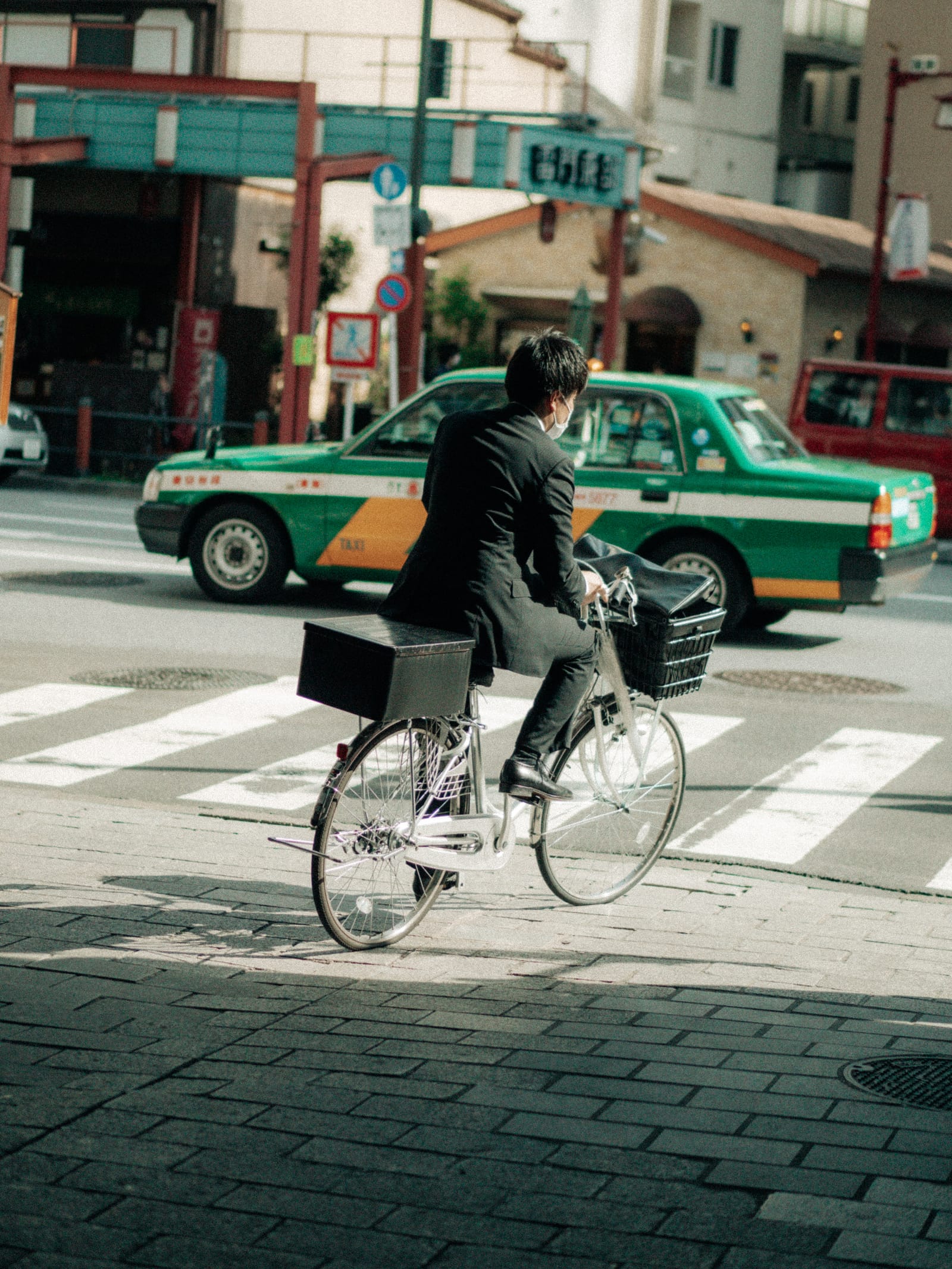 A man in a suit cycling over a crossing in Naha