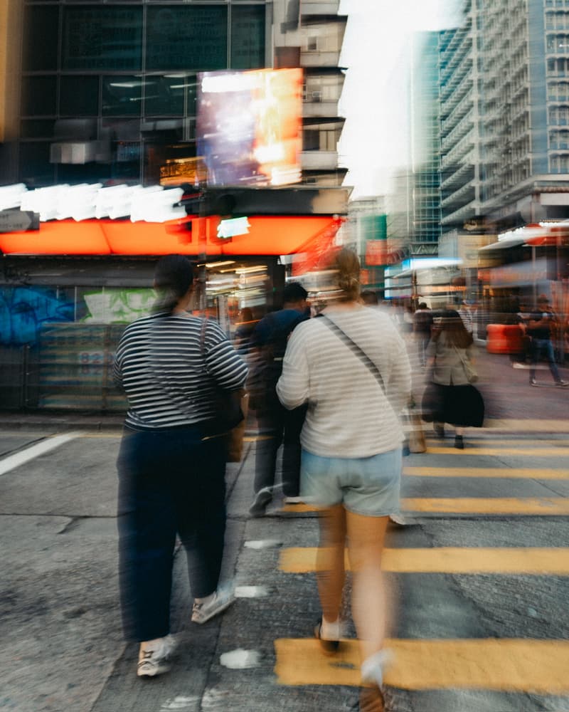 People crossing a busy city street at dusk